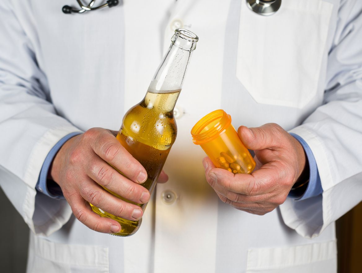 Врач держит в одной руке алкоголь а в другой таблетки